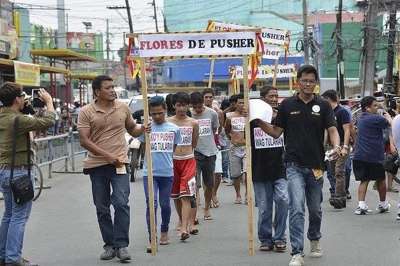 Suspected drug pushers being forced to parade in a "Flores de Pusher" walk of shame on a street in the town of Tanauan, Batangas province, Philippines, on Monday. The placards hanging from the necks of the 11 alleged drug pushers read: "I am a pusher