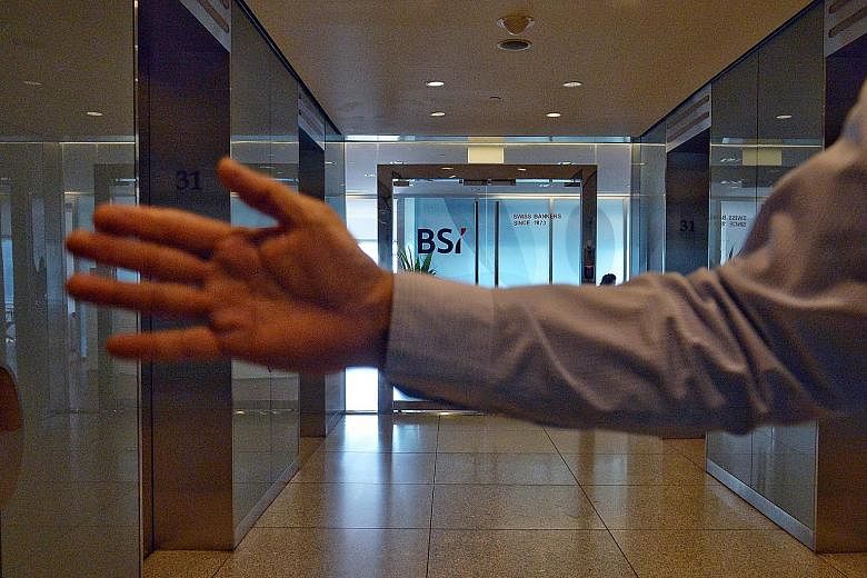 A staff member blocking the media from taking photographs of BSI Bank's main office at Suntec Tower One. BSI Singapore said it is operating normally and working to ensure a smooth and quick integration with EFG.