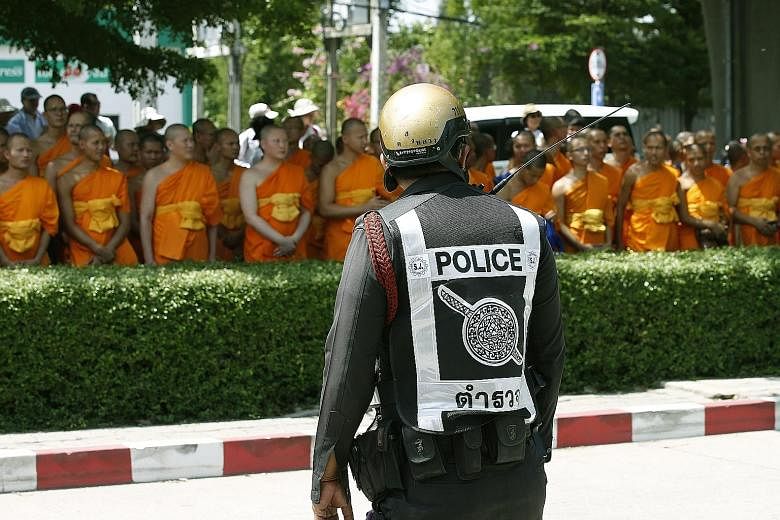 A Thai policeman standing guard yesterday at the Khlongluang provincial police station in Pathum Thani province as Buddhist monks waited for Phra Dhammachayo, the abbot of the controversial Dhammakaya temple, to turn up to face charges of money-laund