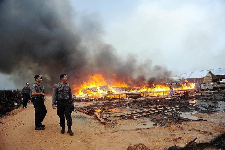 Mobile brigade policemen standing guard after a local mob set fire to the village of followers of the minority religious sect, Gafatar, in Mempawah district in West Kalimantan in January. Human Rights Watch estimates that the group numbered more than