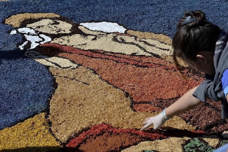A woman from the Archdiocese of Brasilia creating a religious artwork using sawdust, sand and salt on Thursday to celebrate Corpus Christi, a major Catholic festival and a public holiday in Brazil.