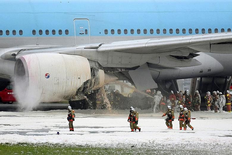 Japanese firefighters spraying foam into the engine of a Korean Air jet that caught fire as the aircraft was preparing to take off from Haneda Airport in Tokyo yesterday. All 319 passengers and crew were evacuated safely. The fire in the left engine 