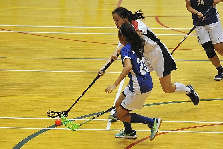 Above: Yishun JC's Ong Swee Ling (white) attempts to get past Meridian JC's Faith Wong. Swee Ling's two goals helped her team regain the A Division girls' floorball title. Left: Joyous Yishun players after beating Meridian 3-2.