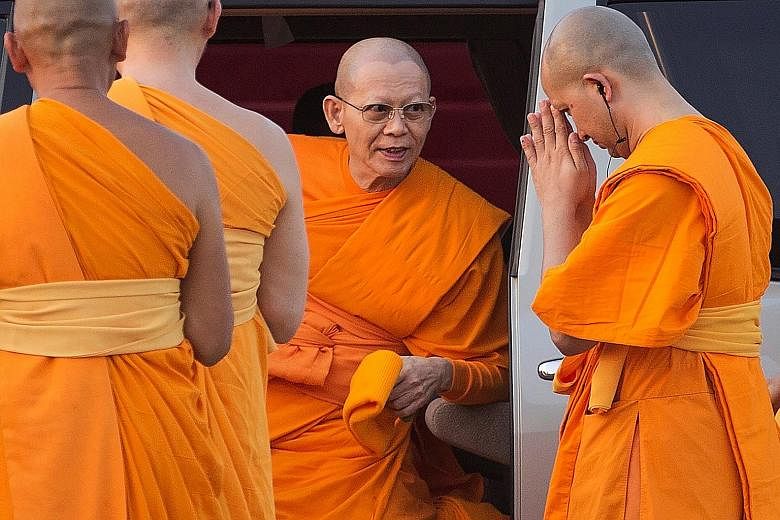 Buddhist monks waiting for Phra Dhammachayo (above) to arrive at the Khlongluang provincial police station in Pathum Thani province on Thursday. The abbot had agreed to hear charges at the police station but did not show up, reportedly having fainted