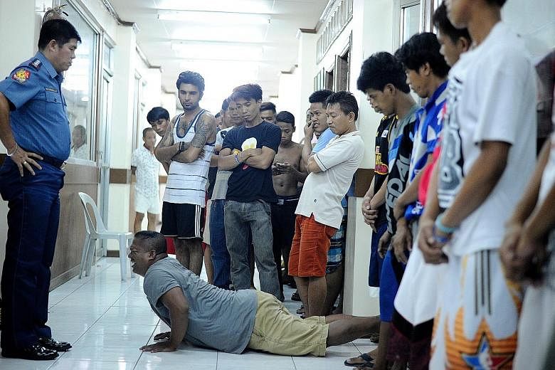 Men caught violating the 10pm liquor ban doing push-ups at a police station in Manila yesterday. The station had implemented "Oplan RODY", or Rid the streets Of Drinkers and Youths as a crime prevention effort.