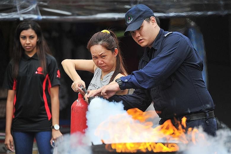 Bank employee Irene Saw, 42, learning how to use a fire extinguisher at the Emergency Preparedness Day held in Chong Pang constituency yesterday. It is the first of six neighbourhoods to pilot the revamped event to help people prepare for possible te