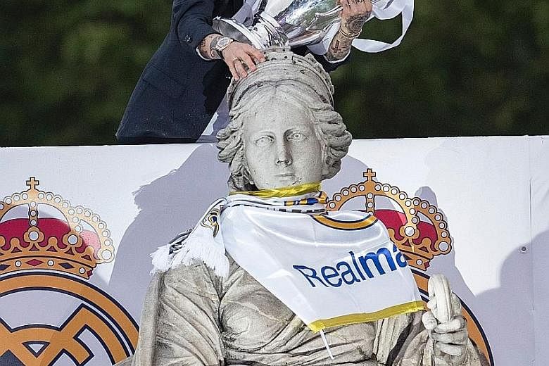 Real defender Sergio Ramos, scorer of the opener, kisses the Champions League trophy in celebration of the team’s win at Plaza de Cibeles in Madrid.