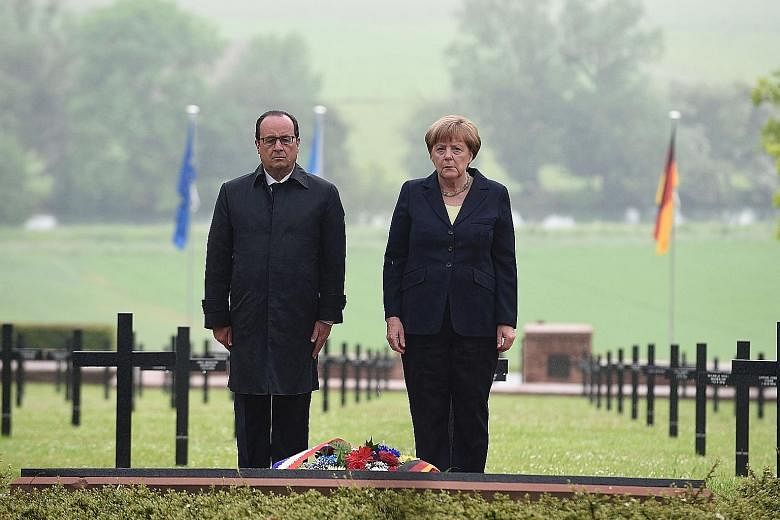 Mr Hollande and Ms Merkel paying their respects at the German military cemetery in Consenvoye, in north-eastern France, where soldiers who died in the 1916 Battle of Verdun are buried.