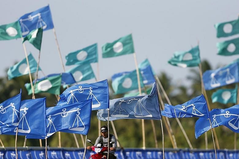 PAS and Barisan Nasional flags next to each other during the 2013 general election. PAS and Umno-led BN, once fierce rivals, are moving closer together as they seek to shore up their political support.