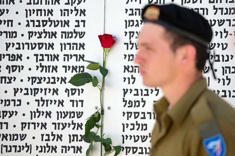An Israeli soldier observing a two-minute silence in front of a commemorative plaque honouring fallen soldiers at the Armoured Corps Memorial, following a ceremony to mark Remembrance Day on May 11 in Latrun, which lies between Jerusalem and Tel Aviv