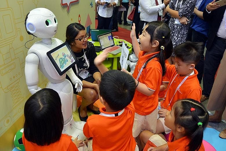 Children interacting with Pepper, one of the two humanoid robots on trial, at the Infocomm Media Business Exchange at Marina Bay Sands yesterday.