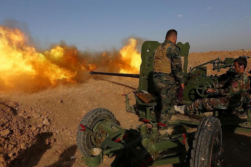 Iraqi Kurdish Peshmerga fighters firing an anti-tank gun on the front line near Hasan Sham village, 45km east of the northern Iraqi city of Mosul, during an operation to retake areas from ISIS.