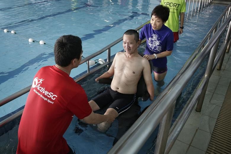Minister for Culture, Community and Youth Grace Fu and Danny Ong, swimming coach and principal trainer for people with special needs at AquaFins, helping amputee Tan Whee Boon into the swimming pool via the ramp. 