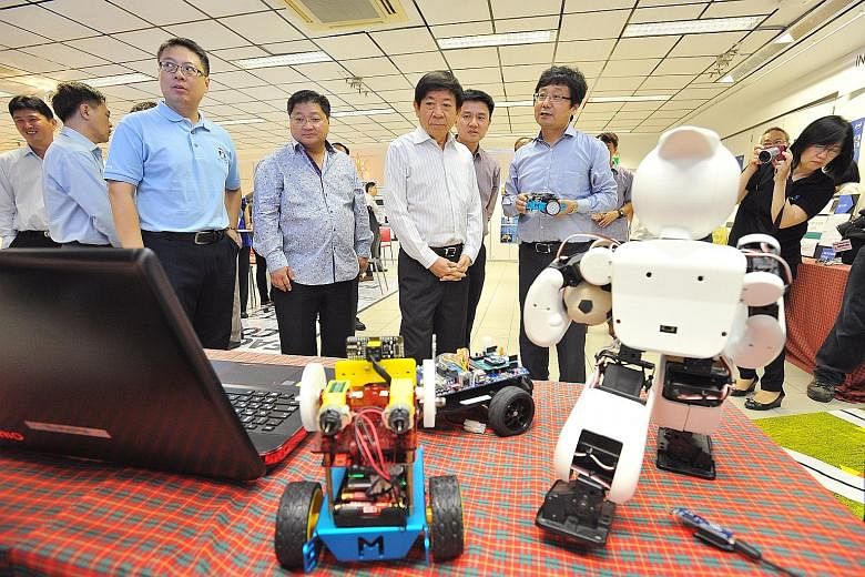 Mr Khaw Boon Wan (centre) on a tour of the new iCt Space at Admiralty Secondary School yesterday. With him were Robotics and Maker Academy director Zhou Changjiu (right) and the school's principal Toh Thiam Chye (behind Mr Khaw). Students will get to