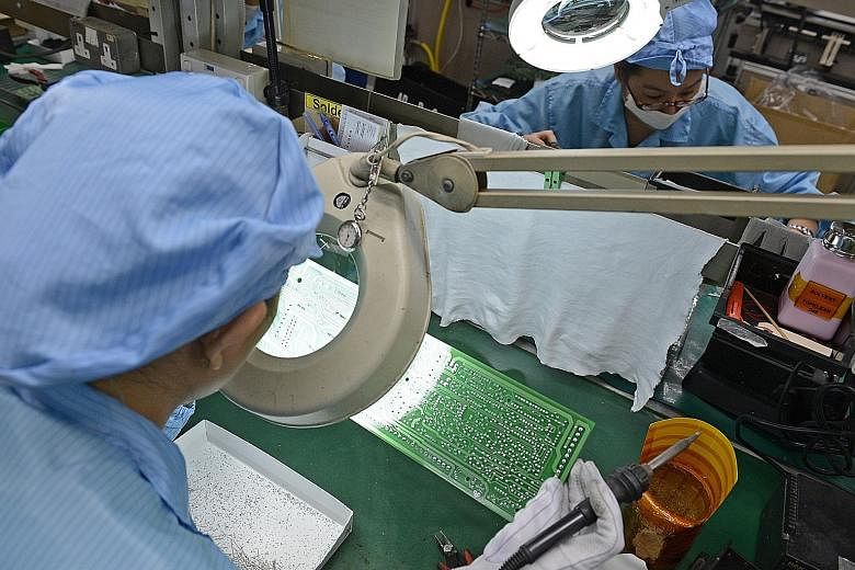 Workers at a company that makes printed circuit boards. The electronics sector posted a PMI reading of 49.1 last month, down from 49.5 in April. Employment in the sector in May contracted for the 13th straight month.