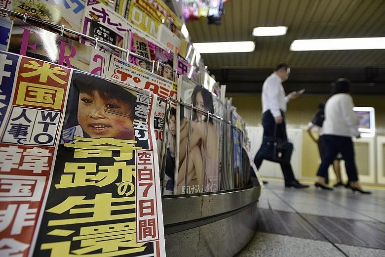 Yamato Tanooka, pictured in a newspaper at a subway kiosk in Tokyo on Friday, was left alone in a forest by his parents as a punishment.