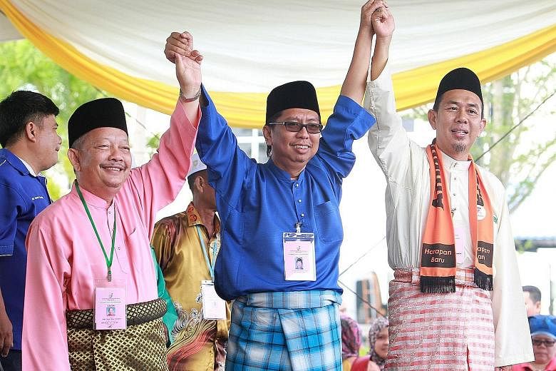 (From left) PAS candidate Abdul Rani Osman, BN candidate Budiman Mohd Zohdi and Amanah candidate Azhar Abdul Shukur sharing a light moment yesterday at the Sungai Besar nominations at Dewan Seri Bernam. The fight there is expected to be close as Umno