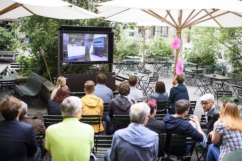 People watching the first projections of the referendum results in Bern yesterday. The proposal sought to introduce a monthly income of 2,500 Swiss francs (S$3,500) per adult and 625 francs per child under 18 no matter how much they work.