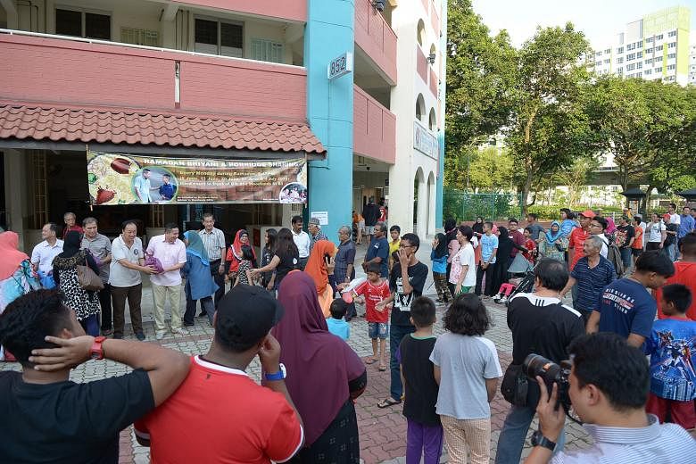 Sembawang GRC MP Mr Amrin (wearing a pink shirt and holding a plastic bag of food) distributing rice and porridge to needy residents in Woodlands yesterday to mark the start of a grassroots charity project. Mr Amrin said the initiative aims to replicate t