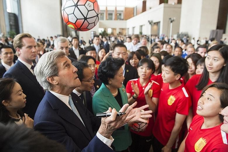 Mr Kerry attempting to head a ball when he and Chinese Vice-Premier Liu Yandong (in green jacket) met the Beijing Normal University women's football team at the National Museum in Beijing yesterday - the closing day of the two-day Strategic and Econo
