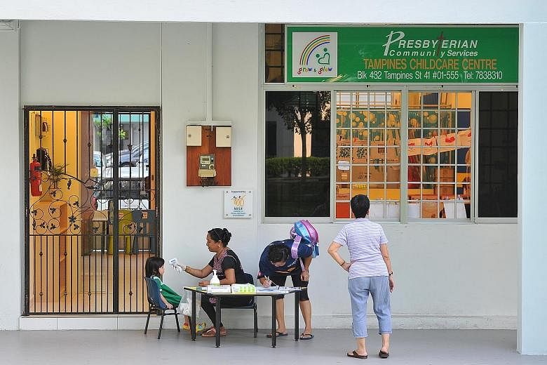 Assistant teacher Kalaichelvi Shanmugam, 49, checking a child's temperature and looking out for blisters before allowing her to enter a childcare centre in Tampines yesterday. Singapore could be heading for one of its worst hand, foot and mouth disea