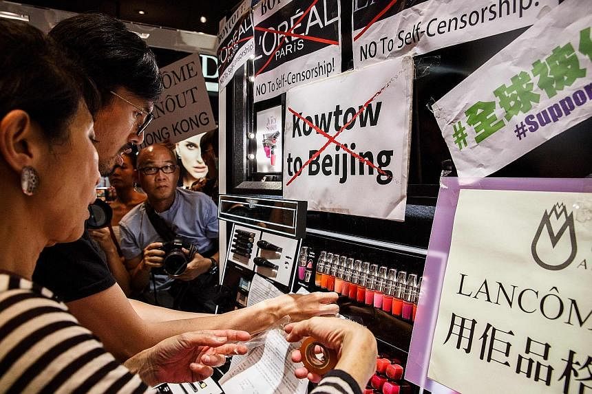 Protesters displaying posters at a Lancome outlet in a shopping mall after the cosmetics giant cancelled a concert featuring pro-democracy singer Denise Ho.