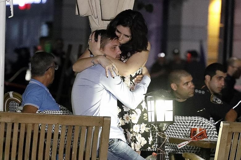 Israelis comforting each other following the shooting attack at a shopping and dining complex in Tel Aviv on Wednesday. At least four people were killed and several wounded in the shooting spree.