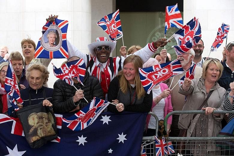 Queen Elizabeth and her husband, Prince Philip, arriving at St Paul's Cathedral in London yesterday to attend a National Service of Thanksgiving to mark the Queen's official 90th birthday. Royal fans with Union Flags and an Australian flag cheering b