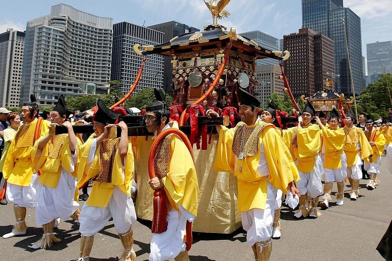 Participants in traditional Japanese garb bearing portable shrines during a parade at the Imperial Palace in Tokyo yesterday. They were taking part in the Sanno Festival, whose main attraction is a nine-hour-long parade by hundreds of shrine-carrying