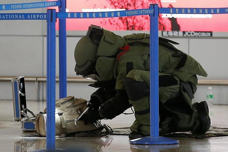A bomb disposal expert checking a bag near the site of the attack. The incident took place near a check-in counter of Terminal Two at the Pudong International Airport. Medical attendants wheeling away a person on a gurney. Video clips online showed d