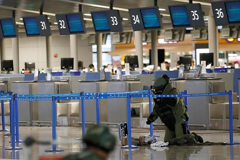A bomb disposal expert checking a bag near the site of the blast at Pudong International Airport on Sunday. Zhou threw a beer bottle packed with explosives before slashing himself in the neck.