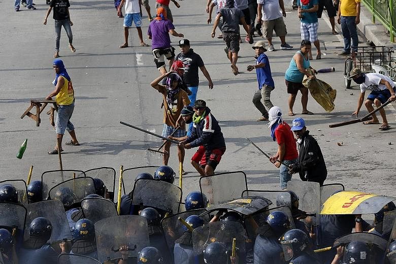 Filipino informal settlers clashing with anti-riot police yesterday during a demolition of shanties in Quezon city in the east of Manila in the Philippines. According to local news reports, scores were hurt during the stand-off, including members of 