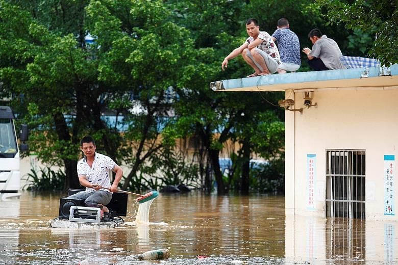 A man using a foam board as a raft to take electronic devices away from a flooded building in Liuzhou, Guangxi Zhuang Autonomous Region, in south China yesterday after a sudden storm turned streets into rivers.