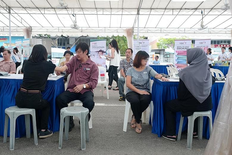 Workers taking advantage of a free medical check-up in a pop-up tent at Tampines Industrial Park A, organised by HPB as part of the Healthy Workplace Ecosystem initiative.