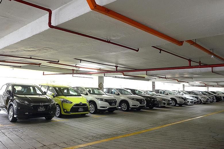 Private-hire cars at a multi-storey carpark near Beach Road on Wednesday. The number of such cars, used for picking up paying fares, is catching up with the total number of taxis owned by cab firms.