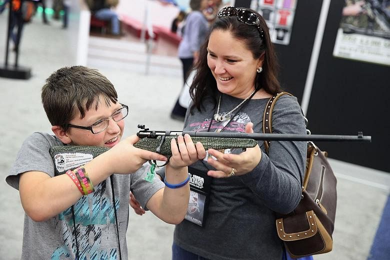 Zane Reynolds, 10, and his mother Jamie looking at a rifle at the NRA Annual Meetings and Exhibits on May 21 in Louisville. The .22-calibre rifle is designed to help children learn how to shoot. About 80,000 visitors attended the event. NRA is an inf