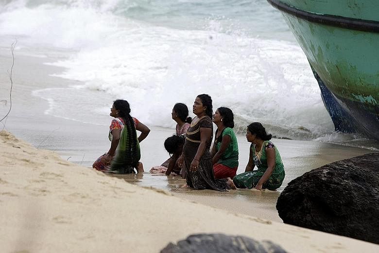 Some of the Sri Lankan migrants begging the Indonesian authorities for help yesterday as they knelt on Lhoknga Beach next to their boat.