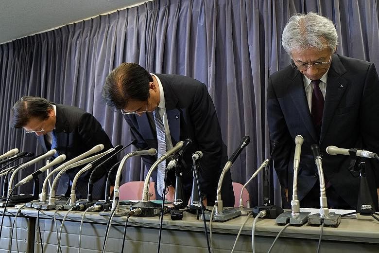 Top: The Mitsubishi headquarters in Tokyo, Japan. Above, from left: Mitsubishi Motors president Tetsuro Aikawa, chief executive Mr Masuko and executive vice-president Ryugo Nakao apologising during a press conference in Tokyo yesterday. The company s