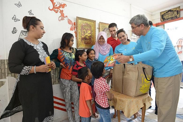 Left: Dr Yaacob presenting books and food items to Madam Zeenat (far left) and five of her six children yesterday, as part of Mendaki's annual charity drive. With Dr Yaacob are (from left) Mendaki CEO Tuminah Sapawi, Mr Necmettin Eskici, director of 
