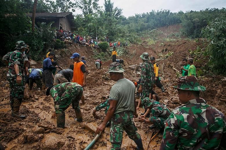 Indonesian soldiers (above) searching for landslide victims at Caok village in Purworejo, Central Java province, yesterday. Thousands of homes in Central Java have been swamped in water, with the affected areas including Kampung Sewu (below) in the c