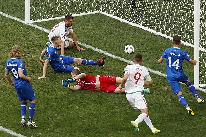 Iceland defender Birkir Saevarsson (left, in blue) looking on in horror after bundling the ball into his own goal to hand Hungary a late equaliser. The two sides shared the spoils 1-1.