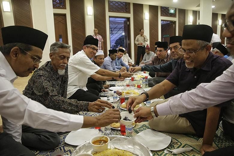 Leaders of the Muslim community sharing a snack of dates as they broke their fast at last night's iftar at the Kampong Siglap Mosque in Marine Parade Road. Some 400 people broke fast together with Minister for Communications and Information Yaacob Ib