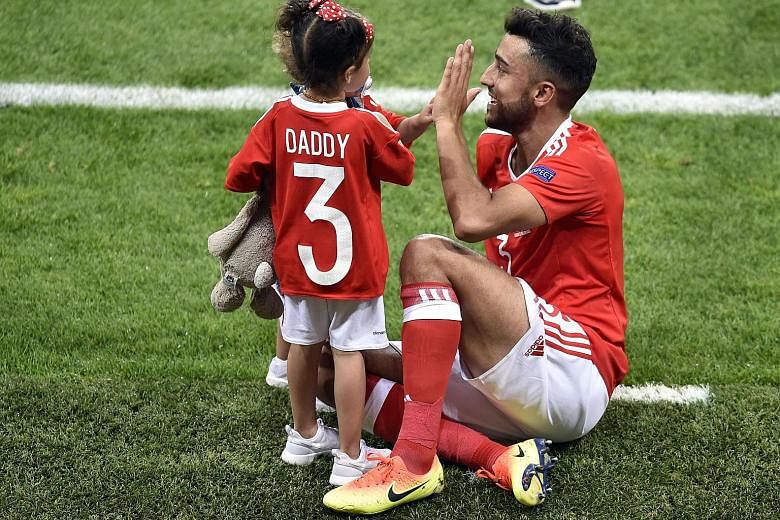 Wales defender Neil Taylor celebrates his side's 3-0 Group B win over Russia with his children. He scored the second goal of the match as Wales trounced a poor Russian side and finished as Group B winners.