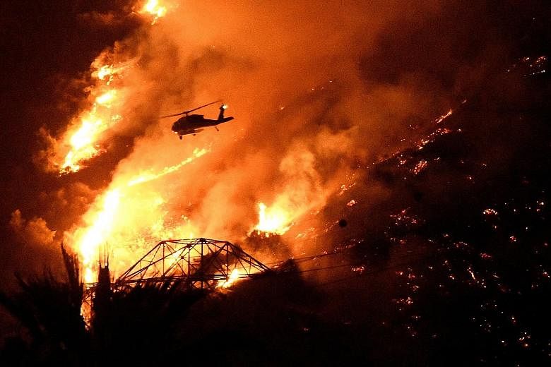 Below: A fire helicopter making a night drop while battling a blaze above Azusa, California, on Monday.
