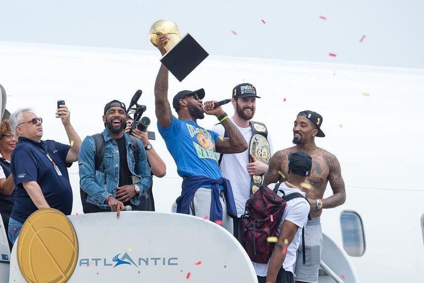LeBron James (holding trophy) taking a gentle jibe at their' defeated Finals opponents Golden State Warriors, as he emerged from the team plane sporting an "Ultimate Warrior" T-shirt. 