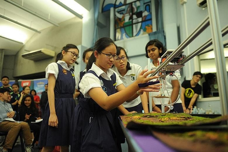 Chang Li-Ann from Raffles Girls' School testing her team's prototype, the V-Wing Fighter, with her teammates looking on. They were among the 240 students involved in a competition under the Fuel Your School - Stem @ Central Singapore initiative held 
