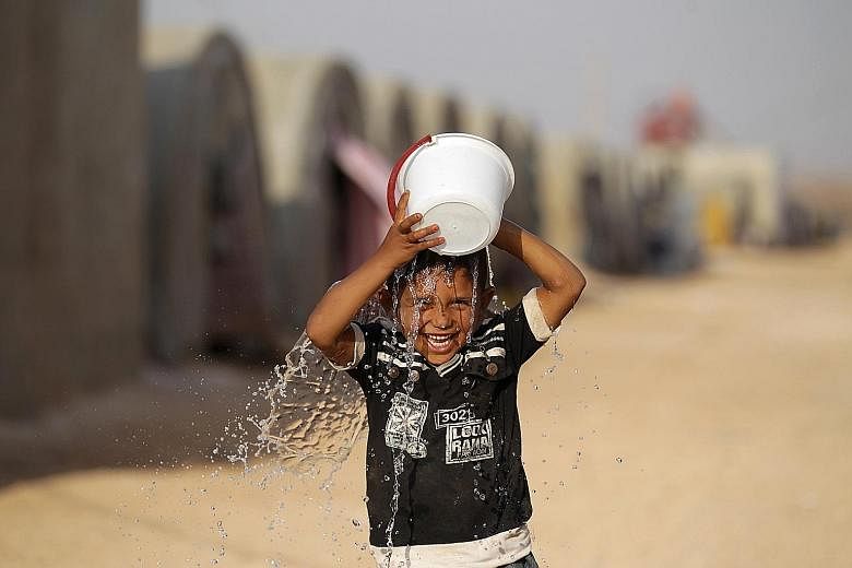 An internally displaced Syrian boy pouring water on his head to cool off in Jrzinaz camp, in the southern part of Idlib, Syria, this week. Temperatures have been creeping upwards in recent days, with the maximum expected to hit about 40 deg C today.