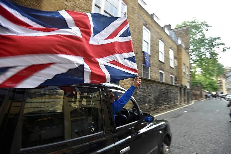 UK Independence Party leader Nigel Farage and "Leave" supporters cheering the referendum outcome yesterday. He had said Prime Minister David Cameron should immediately resign if Brexit became a reality. A taxi driver in central London displaying a Un