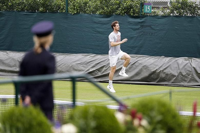 Andy Murray, the 2013 champion, warming up before training at Wimbledon while being watched by a member of the security staff. He is tipped to face world No. 1 Novak Djokovic in the final.