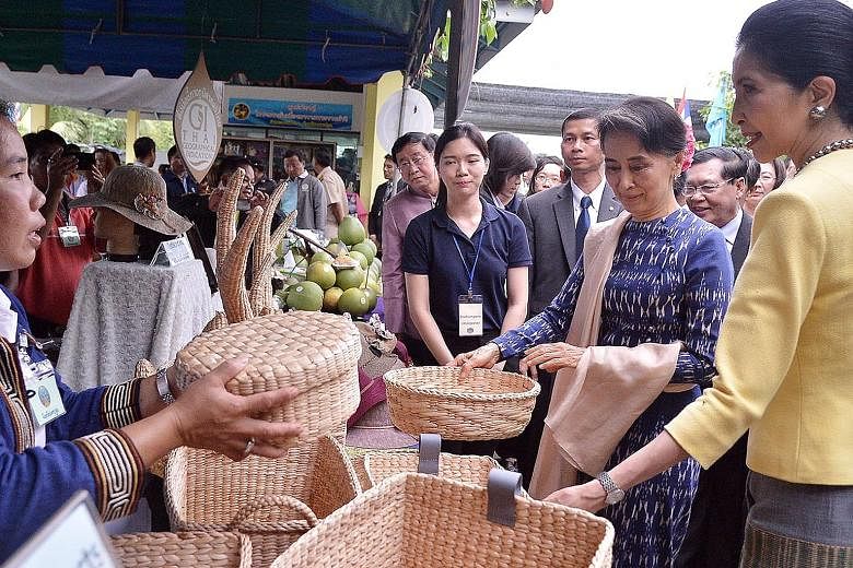Ms Suu Kyi (second from left) and the Thai Prime Minister's wife Naraporn Chan-o-cha (left) looking at traditional crafts during their visit to a learning centre in Nakhon Pathom province, Thailand, yesterday. Ms Suu Kyi is on an official visit to th
